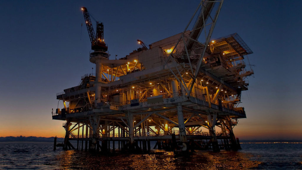 image of an oil rig facility far from the coast in the sunset