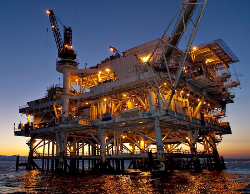 image of an oil rig facility far from the coast in the sunset