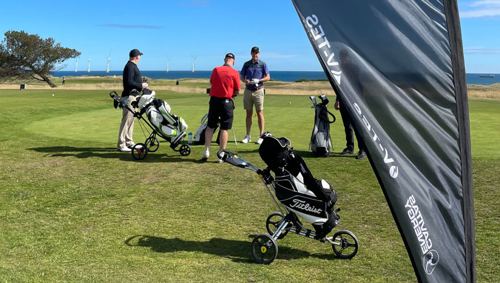 golfers getting ready to play on a field near the coast